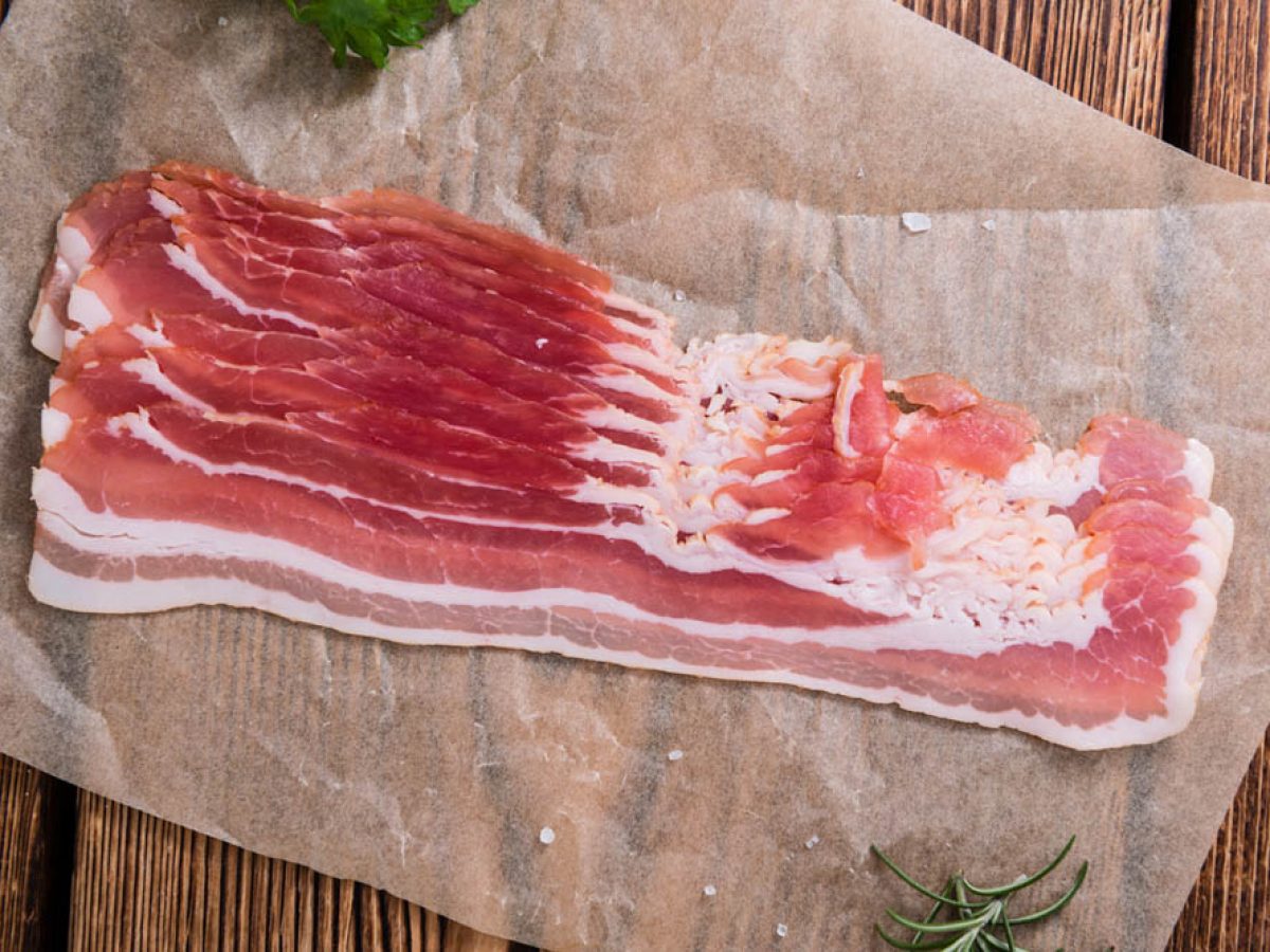 Portion of raw Bacon stripes on wooden background (selective focus)